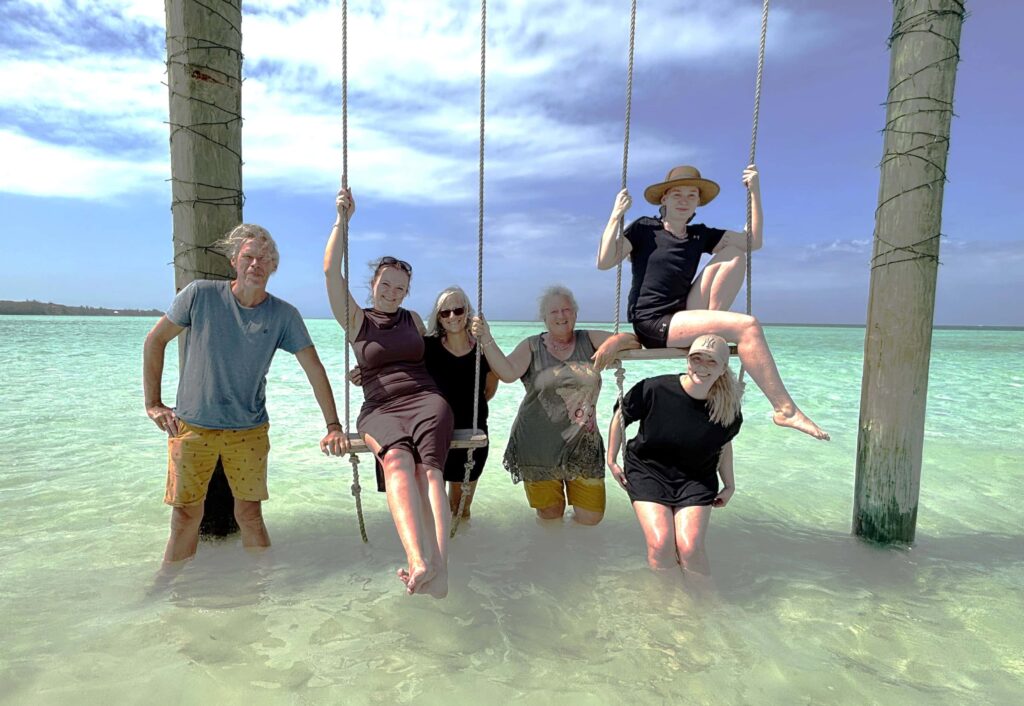 Bahamas - Eleuthera - mit dem Golfcart unterwegs in Spanish Wells & Russell Island 20 Bahamas Crew der Blue Joline am traumhaften Bahama Strand. Das Wasser ist warm die Schaukel eine schöne Abwechslung und Fotomotiv für ein Crewfoto.